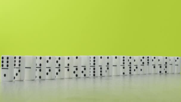 Effetto domino - una serie di domino bianchi che cadono lungo la catena sfondo colorato — Video Stock
