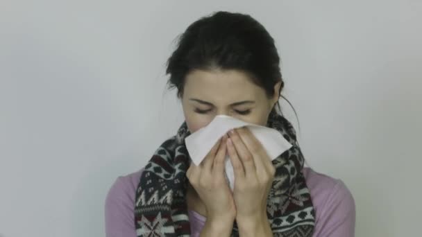 Нездоровая девушка в шарфе с температурой, сморкающаяся на белом фоне — стоковое видео