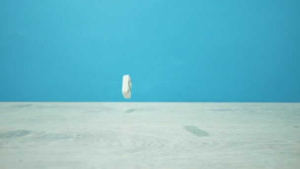 Plan au ralenti de dominos blancs tombant sur un fond d'aigue-marine 