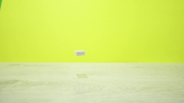 黄色の背景に落ちる白いドミノのスローモーション撮影 — ストック動画
