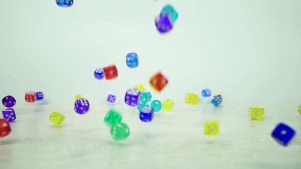 Slow-motion shot van veelkleurige dobbelstenen vallen op een witte achtergrond — Stockvideo