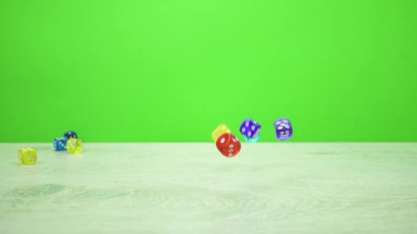 Slow motion shot of multicolored dice fall on a green background — Stock Video