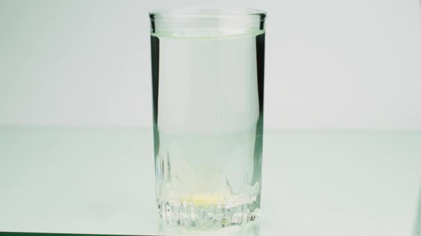 Une pilule effervescente contre la douleur tombe dans un verre et dissout l'aspiration au ralenti sur fond blanc — Video