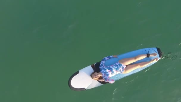 Vista aérea chica bonita se encuentra en un surf en las olas del océano — Vídeos de Stock