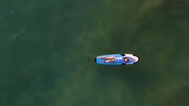 Chica bonita se encuentra en un surf en las olas del océano vista helicóptero con la playa — Vídeos de Stock