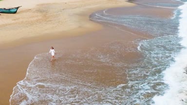 Yavaş hareket hava atış bir sen mutlu kısa beyaz elbiseli kız Okyanusu yakınlarındaki tropikal kumlu plajda yürüyor ve ayaklarını suya ıslatıyor sri lanka, hikkaduwa