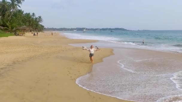 Slow motion aerial shot happy girl running along the ocean shore on holidays — Stock Video