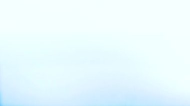 Şeffaf bir su damlası mavi bir sıvının yüzeyine yavaş çekimde düşer..