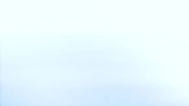 Şeffaf bir su damlası yavaş çekimde kırmızı bir sıvının yüzeyine düşer..