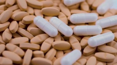 Beyaz antibiyotik kapsülleri parlak turuncu tabletlerin üzerine düşer. Yakın çekim.