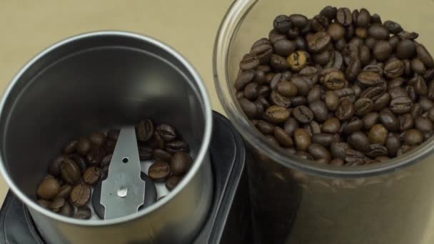 Grãos de café moer em moinho elétrico, fundo bege. Conceito de energia manhã — Vídeo de Stock