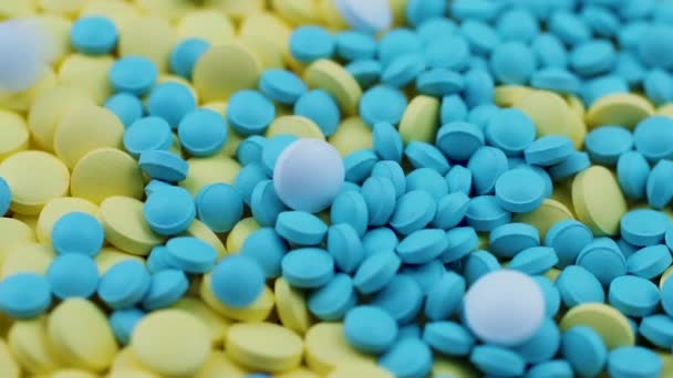 Les remèdes homéopathiques blancs tombent sur des pilules jaunes et bleues éparpillées sur la table — Video