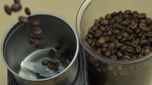 Grãos de café caem em moedor elétrico, fundo bege. Conceito de energia manhã — Vídeo de Stock