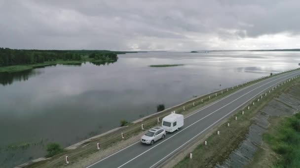 En bil med husvagn kör längs en damm över floden i Kanada. Landskap — Stockvideo