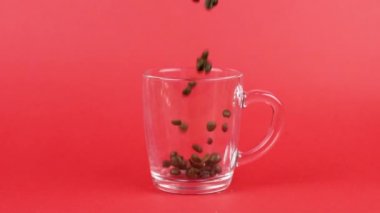 Kahve çekirdekleri hızla uçar, cam bardaklar birbirine karışır, kırmızı arka plan. Fazla çalışma kavramı