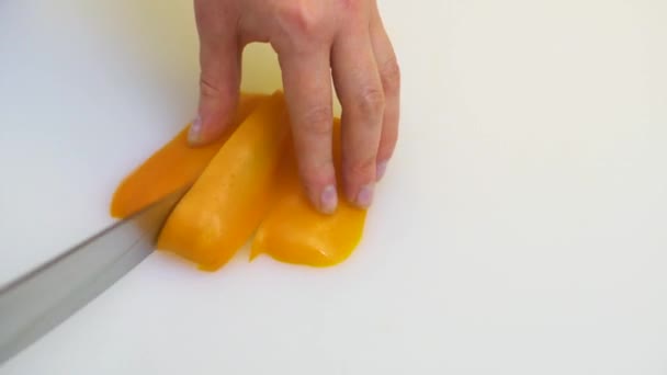 Caucasian woman chef slices a yellow sweet bell pepper with a knife. — Stock Video