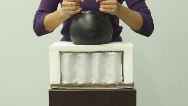 Η γυναίκα βάζει ένα βαρύ βάρος σε ένα ορθοπεδικό στρώμα αφρού — Αρχείο Βίντεο