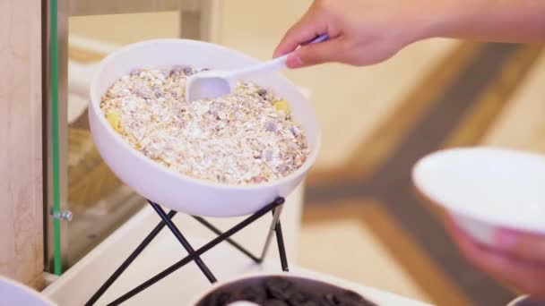 Man puts muesli from a deep bowl into his plate. Hotel restaurant. Smorgasbord. — Stock Video