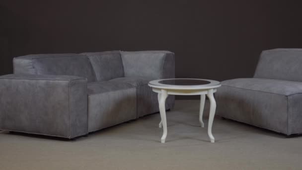 Minimalistyczna kanapa narożna z bogatą aksamitną tapicerką i nowoczesnym stołem — Wideo stockowe