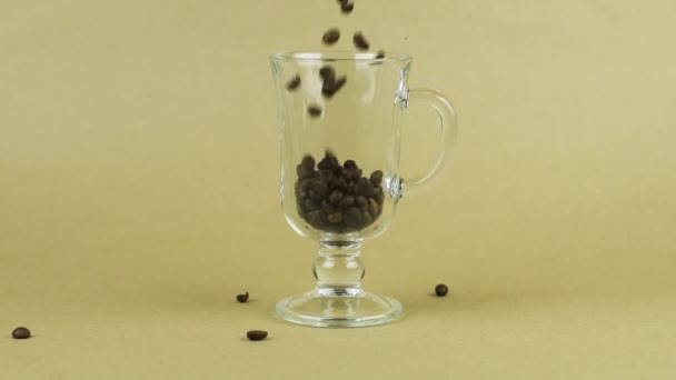 Chicchi di caffè rapidamente volare, tazza di vetro trasparente, sfondo beige. Concetto mattina — Video Stock