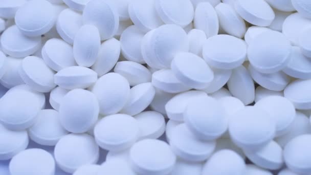 A large number of white pills lie together and rotate on a table close-up — Stock Video