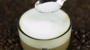 Kahve köpüğünün içine bir kaşık şeker, doğal fasulye arkaplanı. Latte içeriği