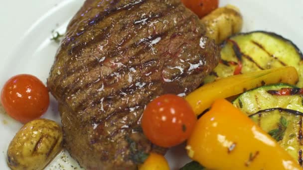 Filete de ternera grasa mignon steak se encuentra en un plato blanco con verduras a la parrilla . — Vídeos de Stock