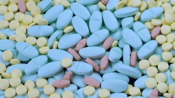 Veel veelkleurige blauwe en gele medicijnen roteren op een tafel close-up — Stockvideo
