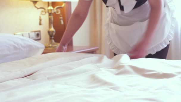 Μια υπηρέτρια στρώνει ένα κρεβάτι σε ένα πολυτελές δωμάτιο ξενοδοχείου. Μεγάλη αγγλική υπηρεσία. — Αρχείο Βίντεο