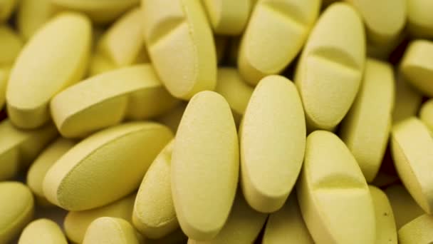 Leuchtend gelbe Antibiotika und antivirale Pillen liegen zusammen und drehen sich in Großaufnahme — Stockvideo