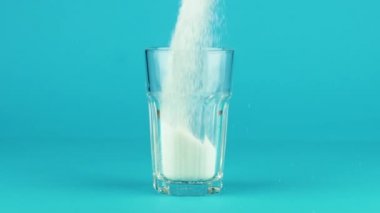 Şeker Collins 'in bardağını kalın alttaki mavi zıt zıt arka planı yavaş çekimde dök