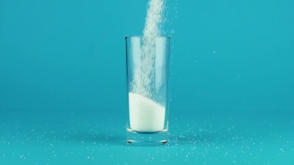 Налийте цукор склянку високого м'яча товстим дном синім контрастним фоном повільний рух — стокове відео