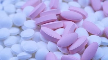 Pembe oval haplar küçük beyaz yuvarlak ilaçlarla birlikte yatar. Döndürmeyi kapat