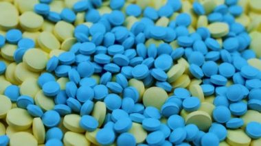 Parlak mavi ve sarı küçük yuvarlak vitaminler masaya uzanıp dönerler..