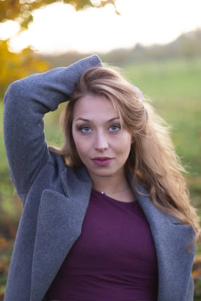 Mulher branca bonita no casaco mantém o cabelo com a mão fora. Parte traseira da natureza — Fotografia de Stock