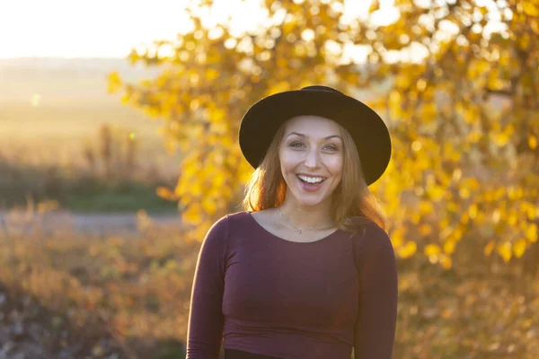 Joyful caucasian girl in hat broadly smiles showing her white straaight teeth