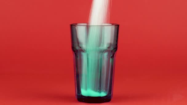Giet suiker groene collins glas dikke bodem rood contrasterende achtergrond. Concept — Stockvideo