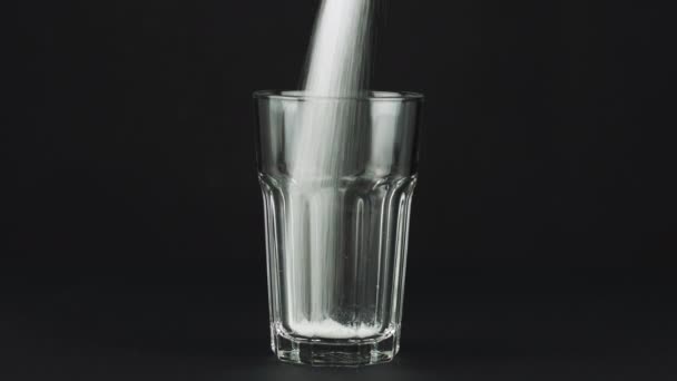Versare zucchero collins vetro fondo spesso sfondo nero a contrasto. Concetto — Video Stock