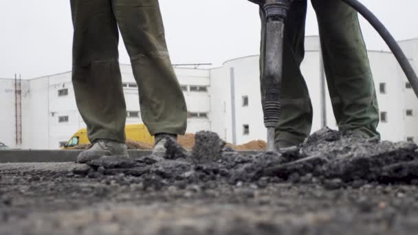 Twee volwassen mannen werken. Vernietig de oude asfaltponsmachine. Bouw een nieuwe weg voor mensen — Stockvideo