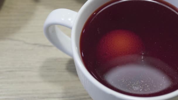 Colorazione dell'uovo di Pasqua in tintura rossa in tazza bianca sul tavolo. Vacanza decorazione suggerimenti — Video Stock