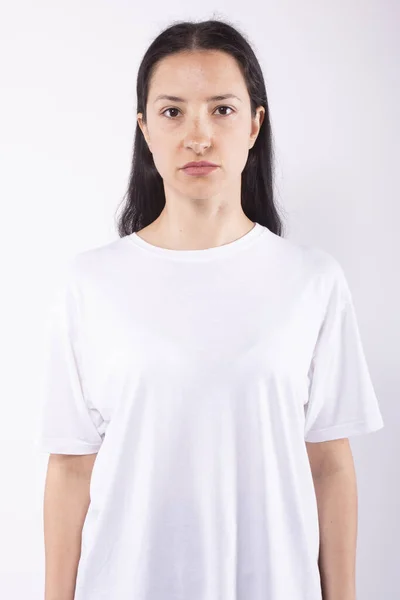 Běloška bez make-upu žena s tmavýma očima v bílém tričku dívá do kamery — Stock fotografie