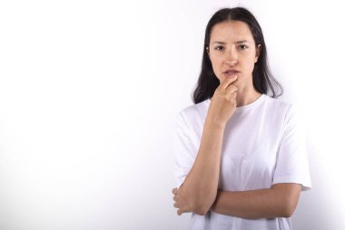 Esmer kadın geçen gülümsemeyle kameraya özenle bakıyor. Eller çenede.