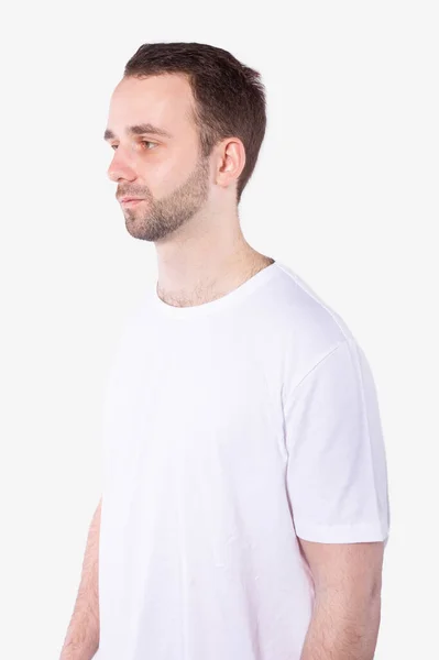 Attractive unshavenman in casual t-shirt stands half-sides and looks ahead — Stock Photo, Image