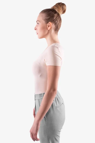 Meisje met blond gebundeld haar staat zijwaarts naar camera en kijkt recht vooruit — Stockfoto