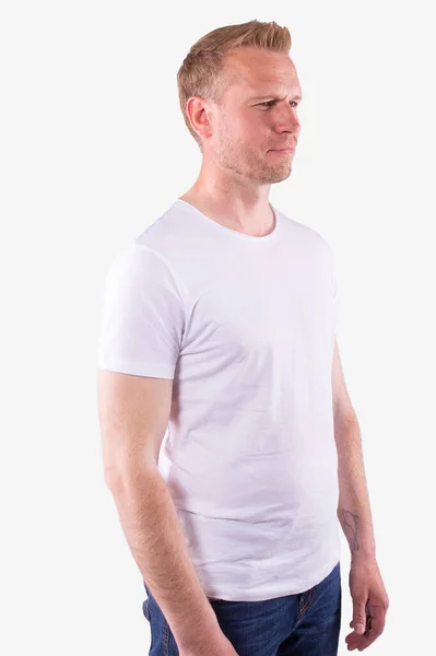 Fehér férfi alkalmi fehér pólóban fél oldalt áll, és egyenesen előre néz. — Stock Fotó