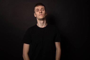 Genç beyaz adam ciddi ve kendine güvenen birine benziyor. Siyah arkaplan