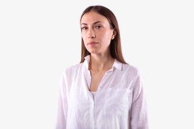 Genç bayan sakin ve kendinden emin bir şekilde kameraya bakıyor. İzole, beyaz arkaplan