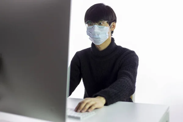 Cerrahi maskeli ve gözlüklü bir Asyalı ofiste çalışıyor. Çin kapanan ülke — Stok fotoğraf