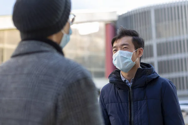 Two chinese men in medical protective masks against covid-2019 talking