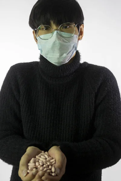 Hombre asiático en máscara facial contra 2019-nCov, puñado de pastillas. Fondo blanco —  Fotos de Stock